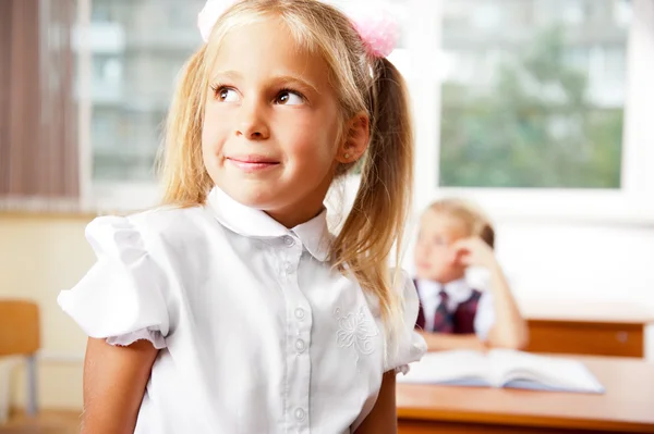Portret van een schoolmeisje wordt in een klas op school met haar Stockfoto