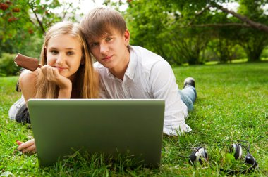 College students using laptop on campus lawn clipart