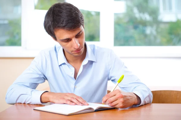 Бизнесмен, сидящий в помещении и пишущий план в дневнике — стоковое фото