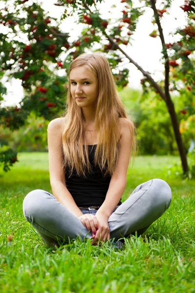 Vacker kvinnlig student sitter utomhus på gräs på campus par — Stockfoto