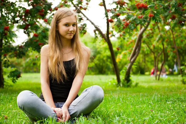 Schöne Studentin im Freien sitzt auf Gras am Campus par — Stockfoto