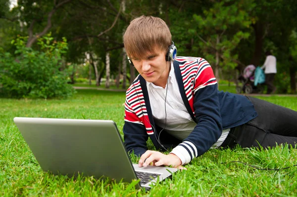 Φοιτητής για τον στο γρασίδι και χρησιμοποιώντας φορητό υπολογιστή εκτός σχολείου — Φωτογραφία Αρχείου