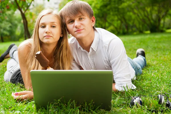Vysokoškoláci používají notebook na trávníku — Stock fotografie