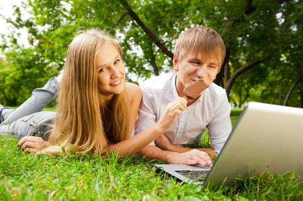 College students using laptop on campus lawn — Stock Photo, Image