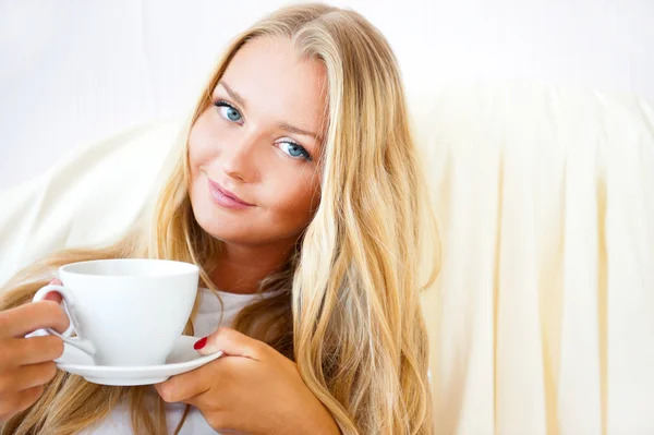 Jeune femme à la maison sirotant du thé ou du café dans une tasse — Photo