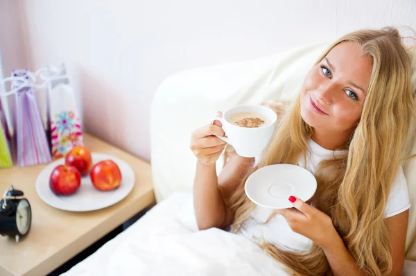 Mladá žena doma popíjeli čaj nebo kávu z hrnečku — Stock fotografie