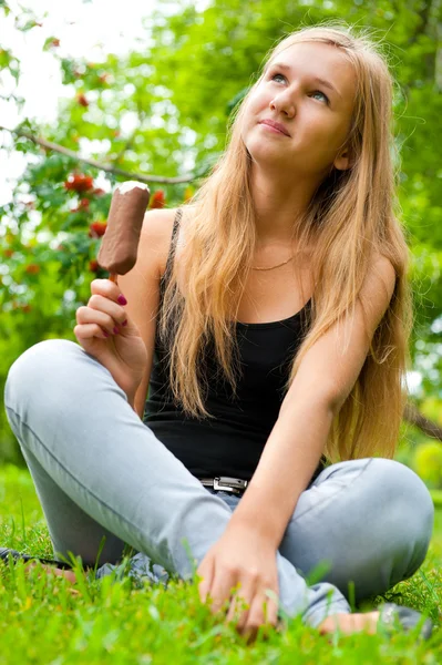 Portret van een jonge vrouw die het eten van ijs zittend ontspannen o — Stockfoto