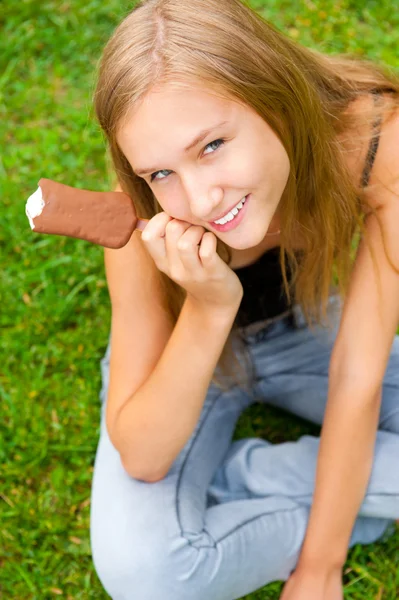 Porträtt av ung kvinna äta glass medan du sitter avslappnad o — Stockfoto