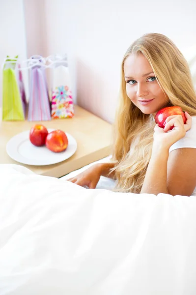 Mladá krásná žena s apple v posteli ráno — Stock fotografie