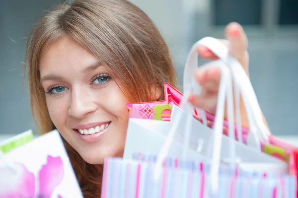 Mulher de compras com lotes de sacos sorri dentro do shopping. Ela está feliz. — Fotografia de Stock