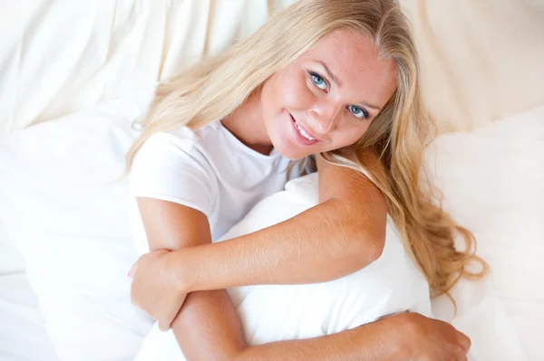 Junge blonde Frau genießt einen sonnigen Morgen im Bett — Stockfoto
