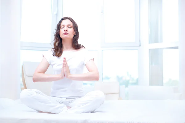 Mladá žena meditací se zavřenýma očima v světlé ložnici dojed — Stock fotografie