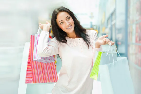 Foto de jovem mulher alegre com sacos de compras no fundo — Fotografia de Stock