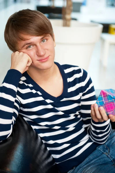 Portrait of young man inside shopping mall sitting relaxed on co