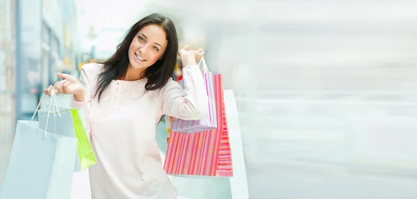 Zdjęcie młodej kobiety radosny z torby na zakupy na tle — Zdjęcie stockowe