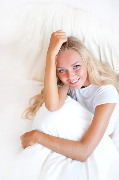 年轻的金发女人享受阳光明媚的早晨在床上。垂直射 — 图库照片