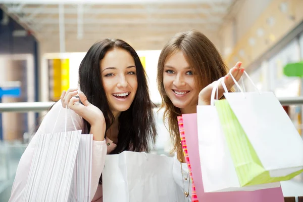 Two excited shopping woman together inside shopping mall. Horizo Royalty Free Stock Images