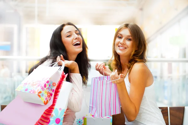 Two excited shopping woman together inside shopping mall. Horizo Royalty Free Stock Photos