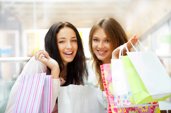 Two excited shopping woman together inside shopping mall. Horizo Stock Picture