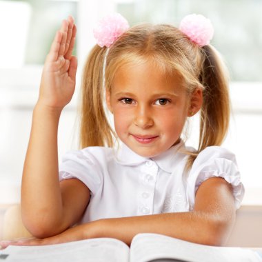 Portrait of a young girl in school at the desk. clipart