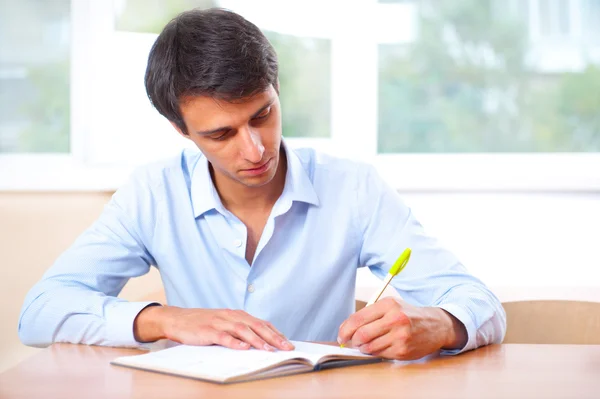 Empresário sentado dentro de casa e escrevendo plano em seu diário — Fotografia de Stock