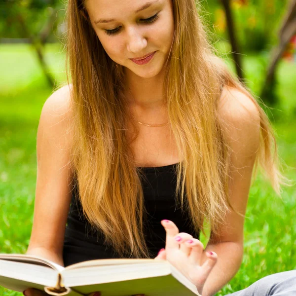 Mooie vrouwelijke student buiten met een boek in campus park — Stockfoto