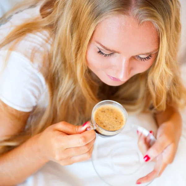 微笑着喝一杯咖啡，躺在家里的沙发上的女人 — 图库照片