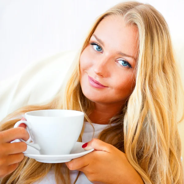 Jovem mulher em casa tomando chá ou café de uma xícara — Fotografia de Stock
