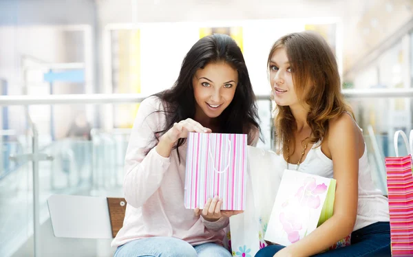 Dos mujeres de compras emocionadas descansando en el banco en el centro comercial Loo —  Fotos de Stock