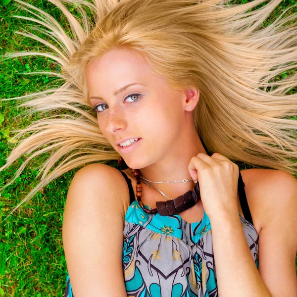 Giovane donna sdraiata su erba verde con i capelli come un sole intorno a lui — Foto Stock