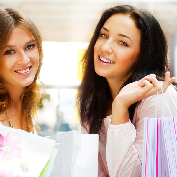 Dos mujeres de compras emocionadas juntas dentro del centro comercial. Horizo —  Fotos de Stock
