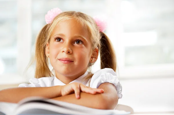 Portret van een jong meisje op school aan de balie. — Stockfoto
