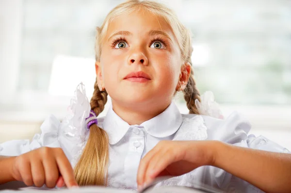 Porträtt av en ung flicka i skolan vid skrivbordet. — Stockfoto
