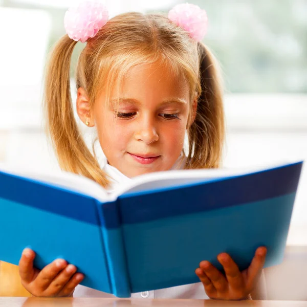 Изображение умного ребенка, читающего интересную книгу в классе — стоковое фото