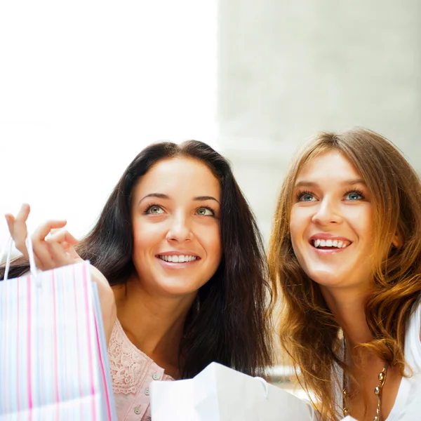 Dos mujeres de compras emocionadas juntas dentro del centro comercial. Horizo Imagen De Stock