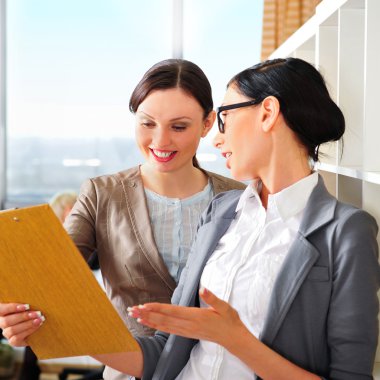 Two business women reading documents clipart