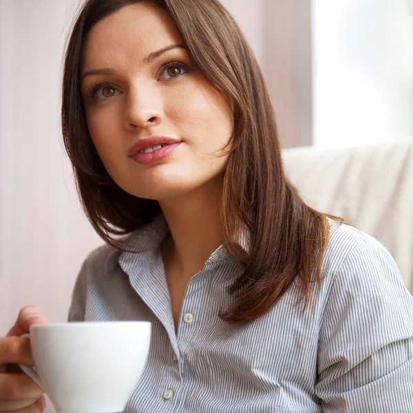Jovem mulher em casa tomando chá de uma xícara — Fotografia de Stock