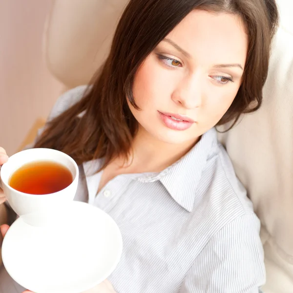 Νεαρή γυναίκα στο σπίτι πίνοντας τσάι από ένα φλιτζάνι — Φωτογραφία Αρχείου