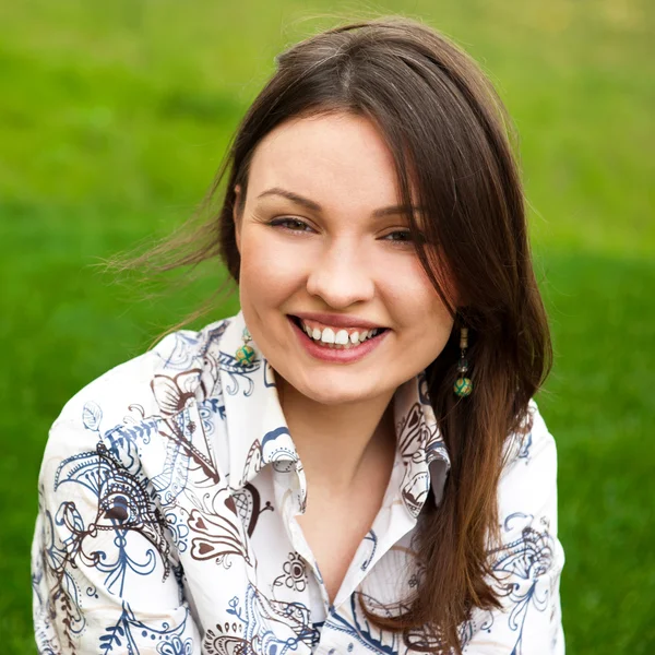 Closeup portrait of pretty young woman resting on grass and smil — Stock Photo, Image