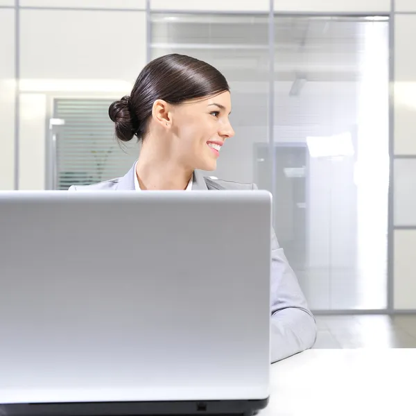 Jeune femme d'affaires sur un ordinateur portable à son bureau. Regard vers l'extérieur — Photo