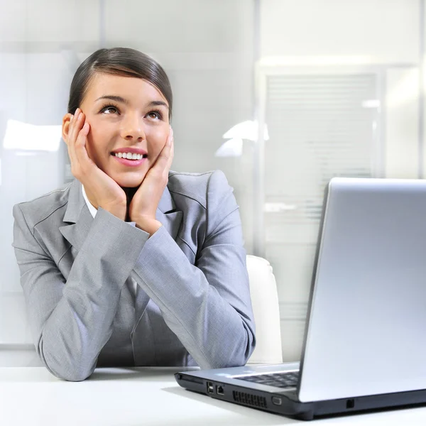 Молодая деловая женщина на ноутбуке в своем офисе. Daydreaming — стоковое фото
