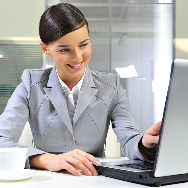 Jonge zakenvrouw op een laptop bij haar kantoor — Stockfoto