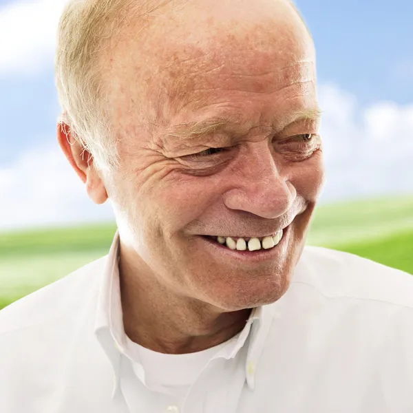 Portrét šťastný starší muž s úsměvem nad světlé pozadí — Stock fotografie