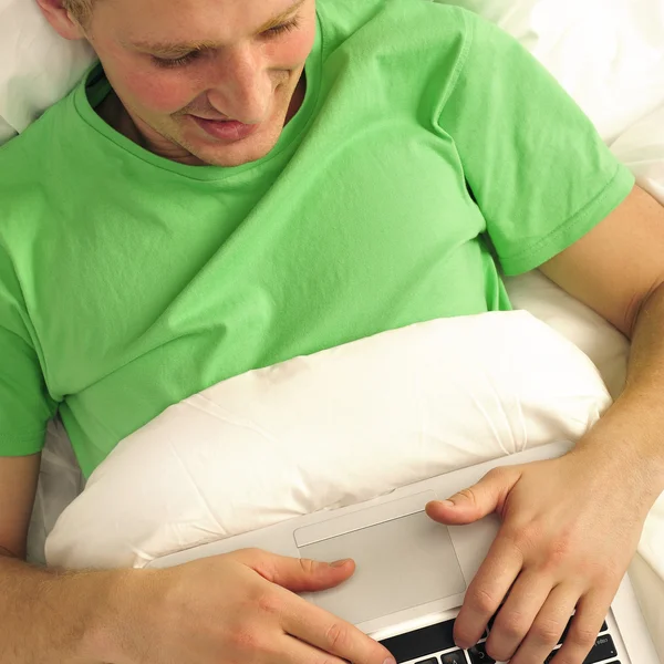 Hombre atractivo relajándose en la cama. Ropa de seda blanca. Trabajar por es —  Fotos de Stock