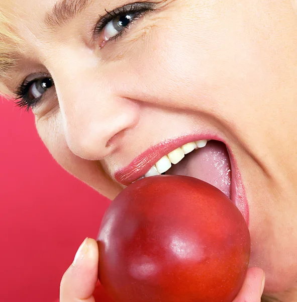 Blonde woman with a peach on a red background — Stock Photo, Image