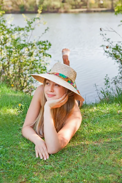Молода блондинка з капелюхом лежить на траві — стокове фото