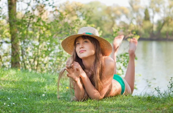 Молода блондинка з капелюхом лежить на траві — стокове фото