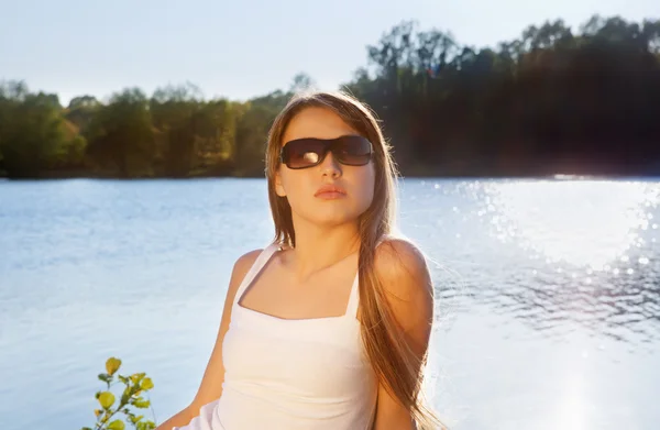 Ung kvinde i solbriller på vandbaggrund - Stock-foto