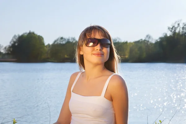 Jeune femme en lunettes de soleil sur fond d'eau — Photo