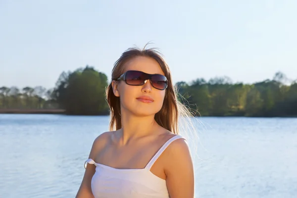 Νεαρή γυναίκα σε γυαλιά ηλίου σε νερό φόντο — Φωτογραφία Αρχείου